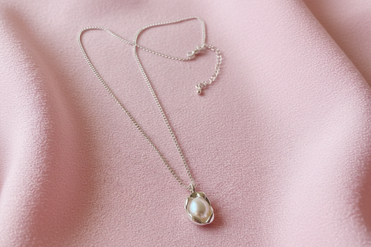 Pearl necklace on a pink fabric background