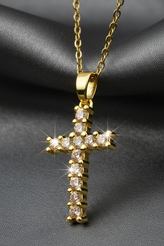 Gold cross pendant with diamonds on a light gray background
