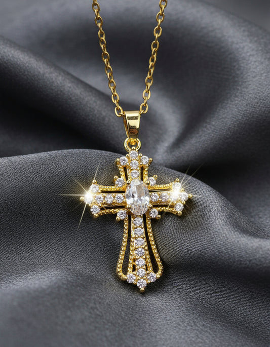 Gold cross pendant with clear stones on a light gray background