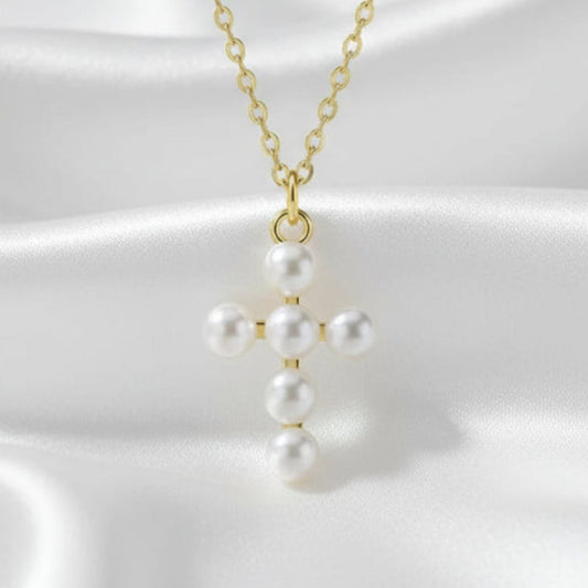 Pearl cross pendant on a gold chain against a white background