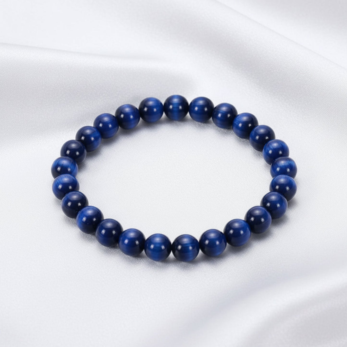 Blue beaded bracelet on a white surface with a stone in the background
