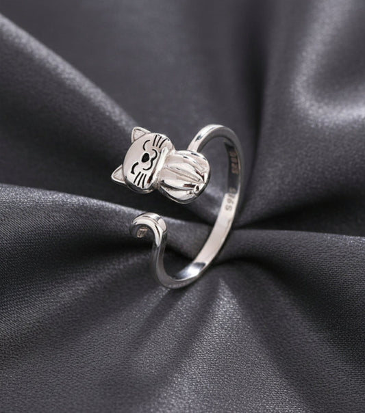 Silver cat-shaped ring on a beige and grey background