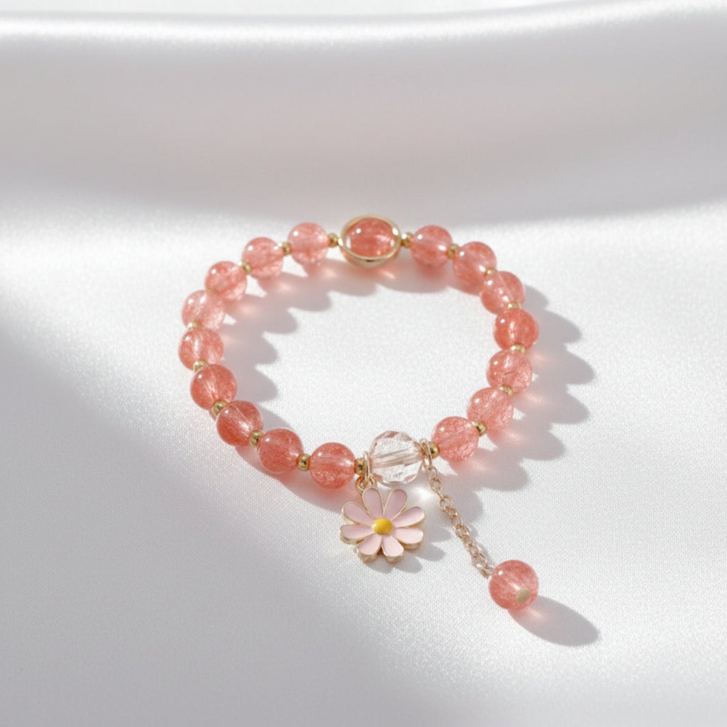 Bracelet with pink beads and a floral charm on a light background