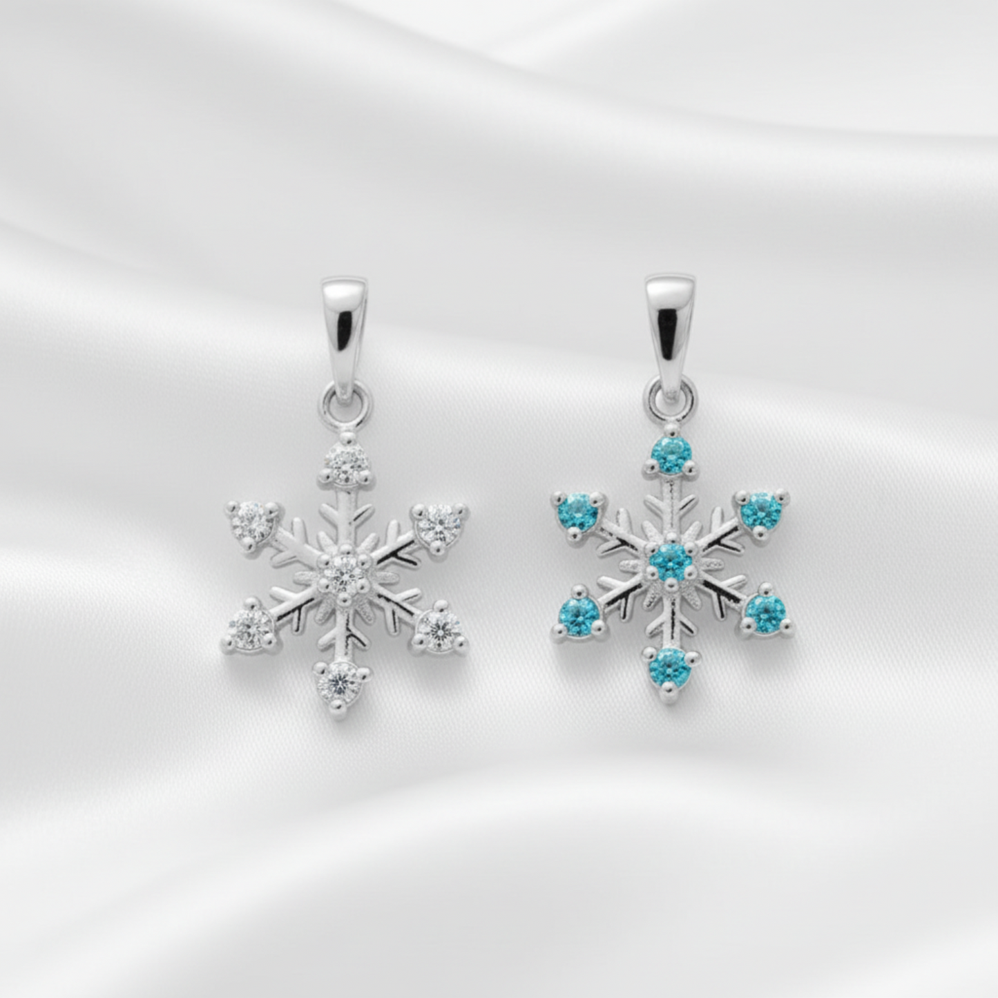 Sterling silver snowflake pendants on a white background. One is clear cubic zirconia and the other is blue cubic zirconia.