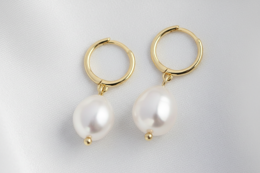 Gold hoop earrings with white pearls on a white background