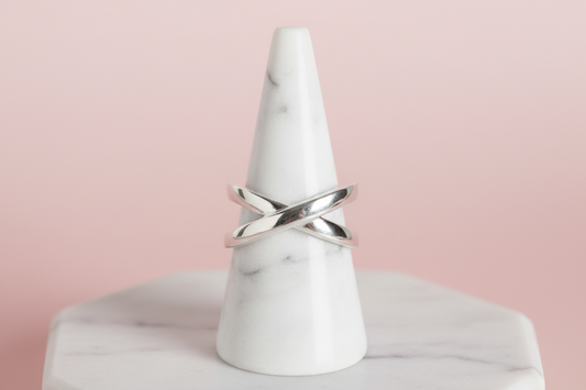 Silver ring on a wooden cone-shaped stand with a blurred background