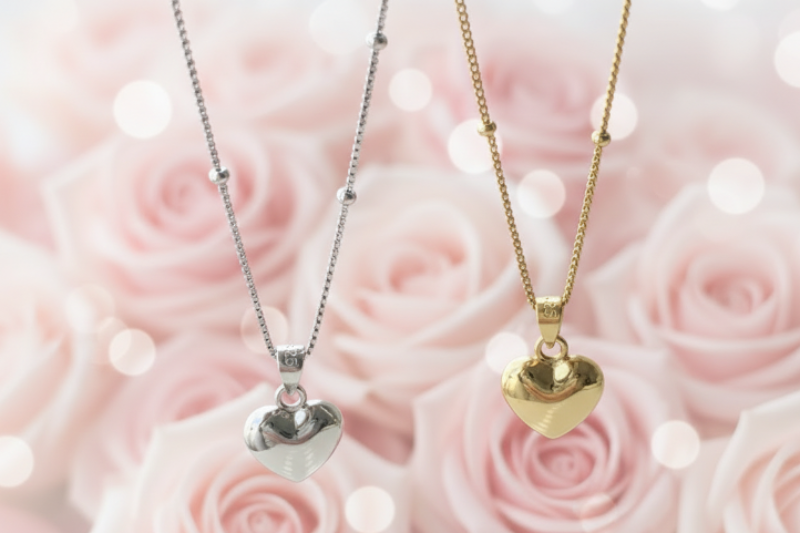 Two heart-shaped pendants on necklaces against a pink rose background