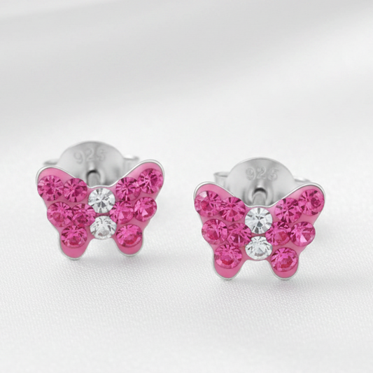 A pair of butterfly-shaped stud earrings with bright pink rhinestones and a central clear crystal, set in silver-tone metal. 