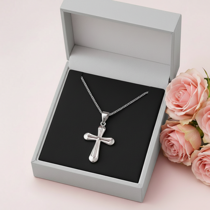 Silver cross necklace in an open black jewelry box on a white background
