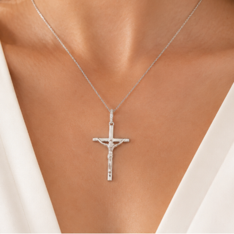 Silver cross necklace on a model wearing a white top