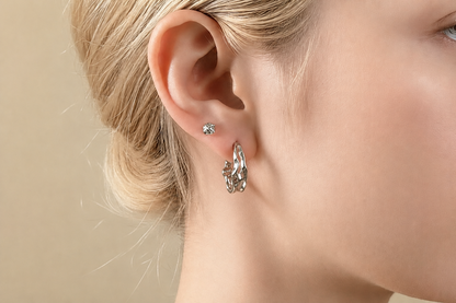 Close-up of a person wearing a silver hoop earring with a small gemstone.