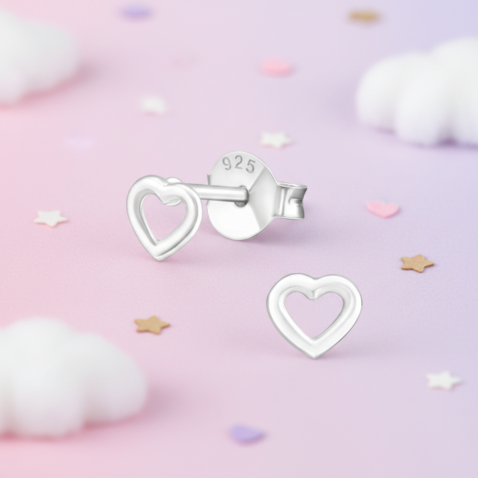 Sterling silver heart-shaped stud earrings, one shown from the front and the other from the back with a '925' stamp, displayed on a pastel pink background with soft white clouds and star confetti.