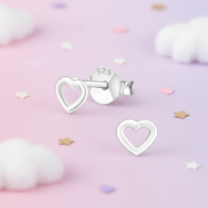 Sterling silver heart-shaped stud earrings, one shown from the front and the other from the back with a '925' stamp, displayed on a pastel pink background with soft white clouds and star confetti.