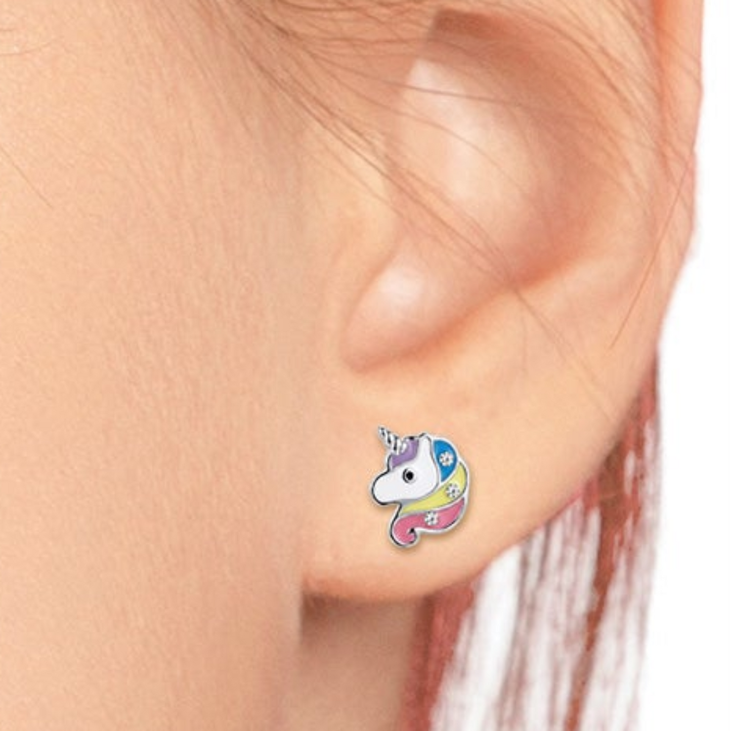 A close-up of a person's ear wearing a small colorful unicorn stud earring. The earring features a white unicorn face with a blue horn and pastel blue, pink, yellow, and purple details.