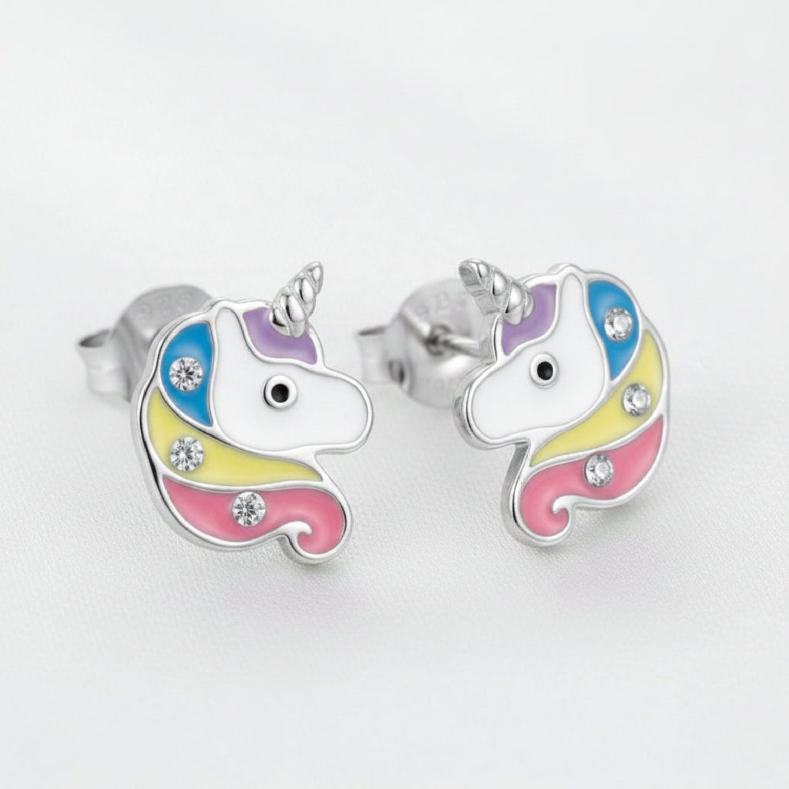 A pair of rhodium-plated unicorn stud earrings with colorful enamel detailing and small crystal accents, shown on a white background.