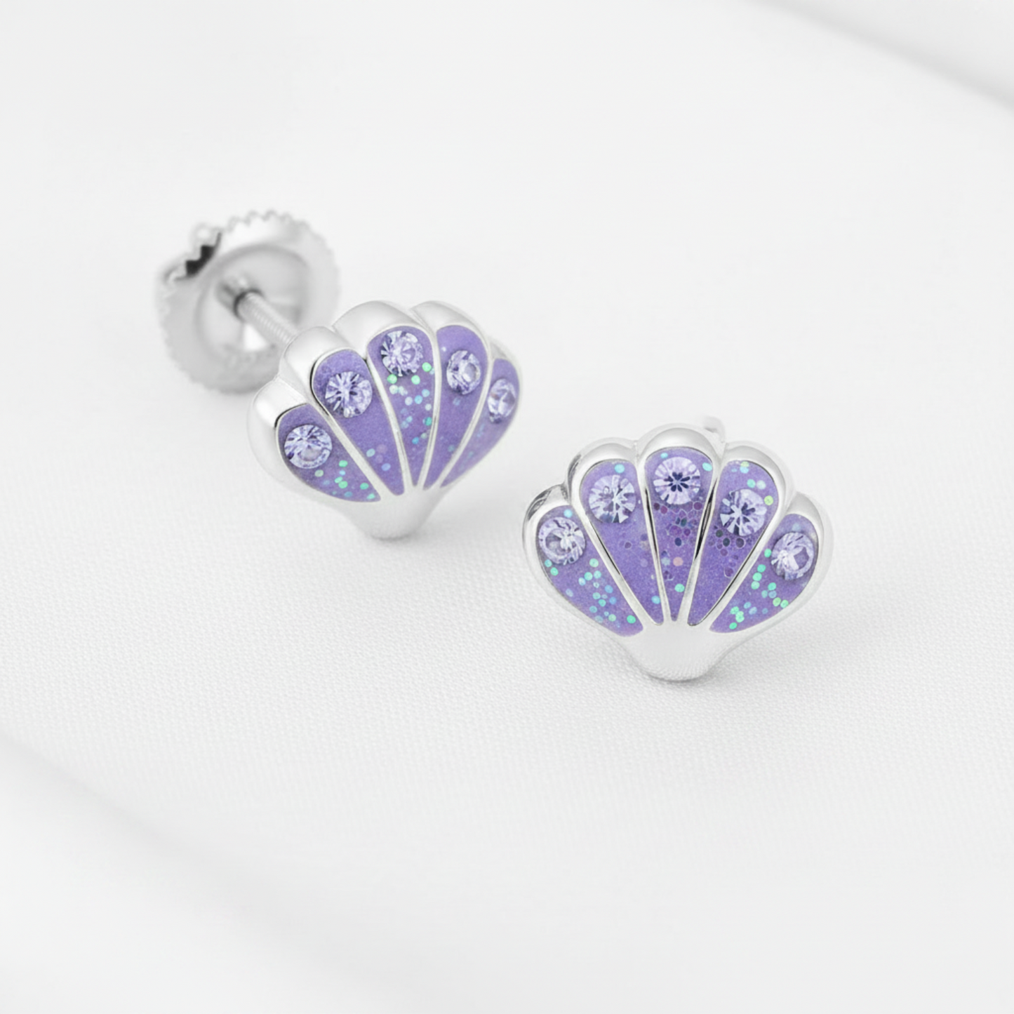 Silver-plated shell-shaped stud earrings with a lavender purple floral pattern and rhinestones, shown on a white textured background with a 'Rhodium PLATED' text overlay and a circular inset demonstrating the rhinestone setting.