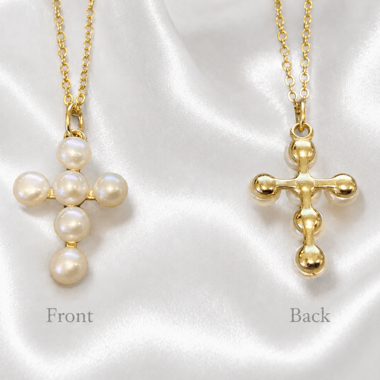 Two gold cross necklaces with pearl details, labeled 'Front' and 'Back', displayed on a white satin fabric background.