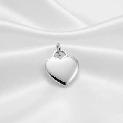 A polished rhodium-plated heart-shaped pendant charm with a small top loop, displayed on draped white satin fabric. The text 'Rhodium PLATED' is visible in the bottom right corner.