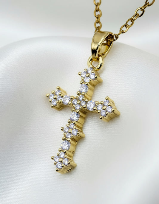 Gold cross pendant with diamonds on a light gray background