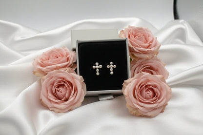 Cross-shaped earrings in a silver box on a white surface