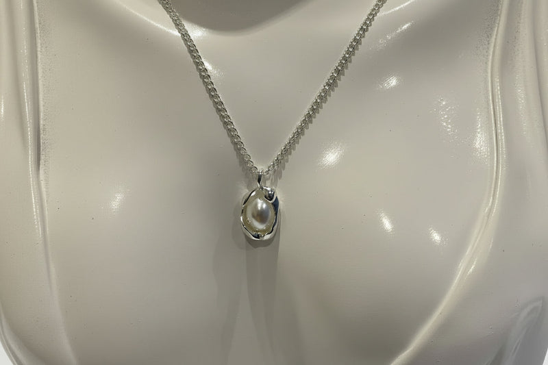 Silver necklace with a pendant on a white mannequin bust
