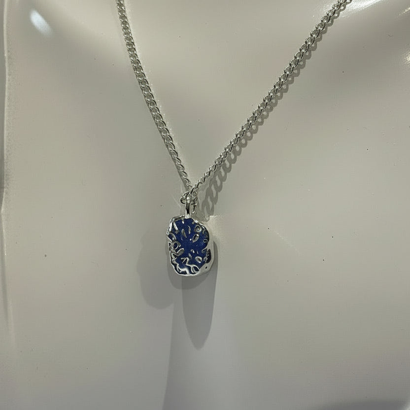 Silver necklace with a blue pendant on a white mannequin bust.