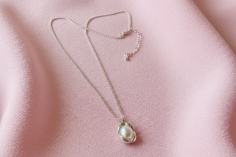 Pearl necklace on a pink fabric background