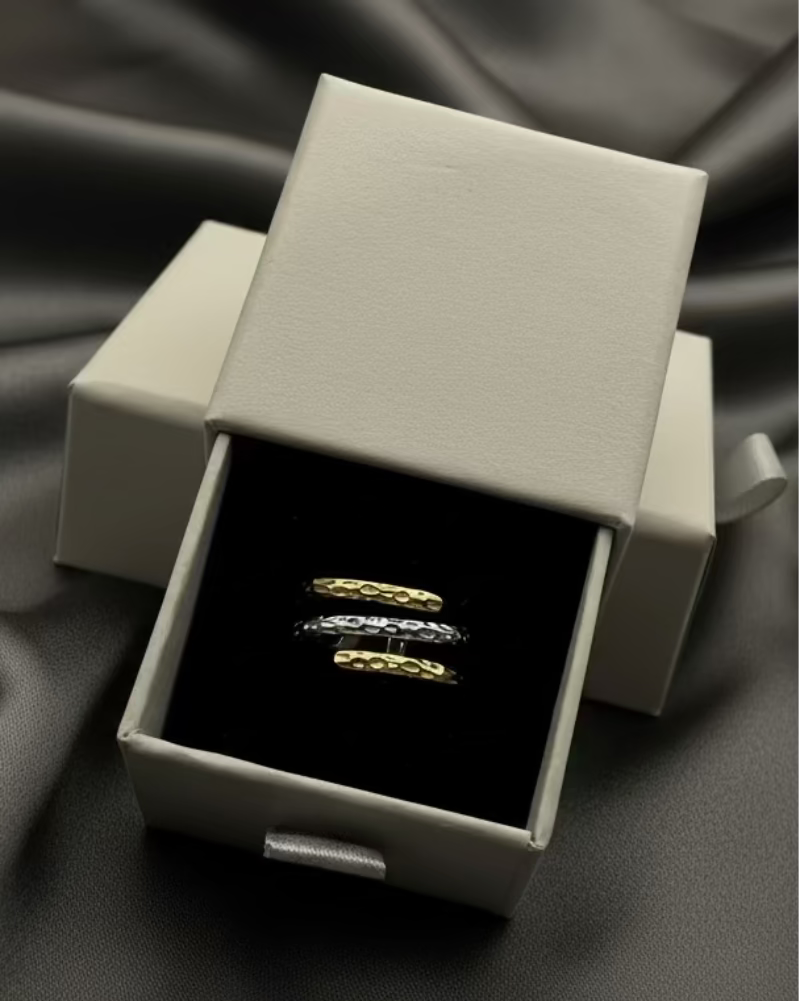 Two gold rings in a silver box on a light gray background