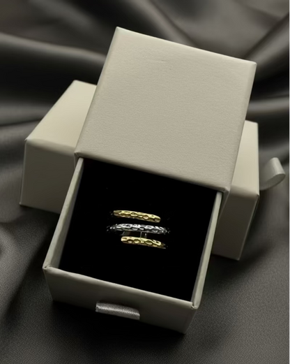 Two gold rings in a silver box on a light gray background
