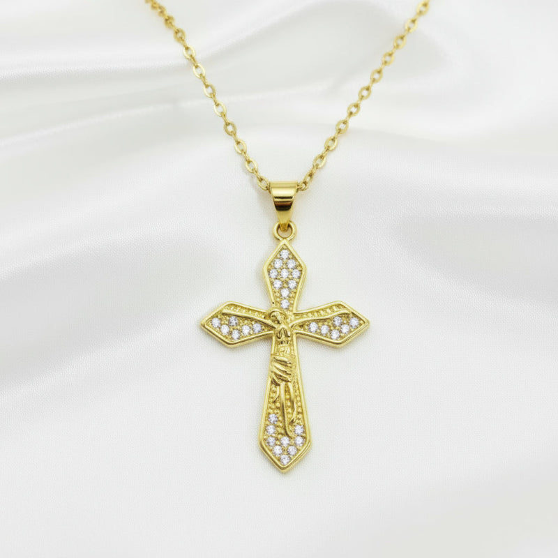 Gold cross pendant with clear stones on a gold chain against a white background