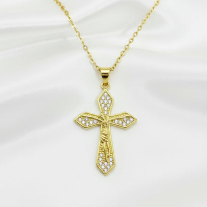 Gold cross pendant with clear stones on a gold chain against a white background
