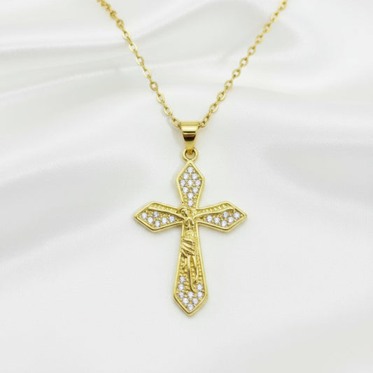 Gold cross pendant with clear stones on a gold chain against a white background