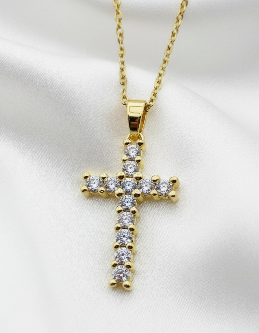 Gold cross pendant with diamonds on a white background