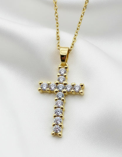 Gold cross pendant with diamonds on a white background