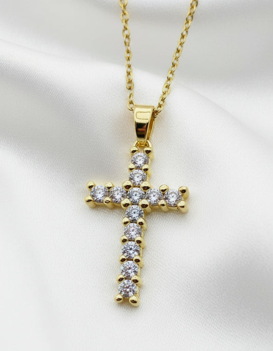 Gold cross pendant with diamonds on a white background