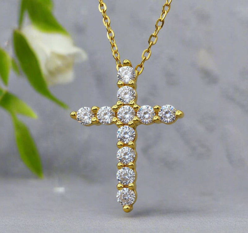 Gold cross necklace with diamonds on a light gray background