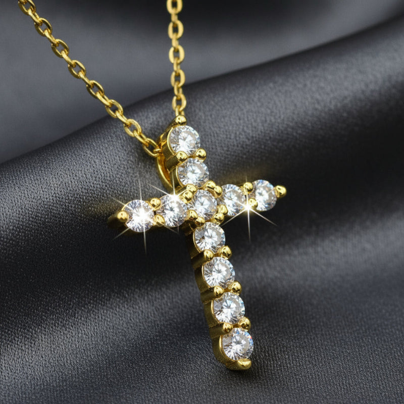 Gold cross pendant with diamonds on a textured gray background