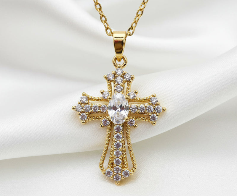 Gold cross pendant necklace with clear stones on a white background