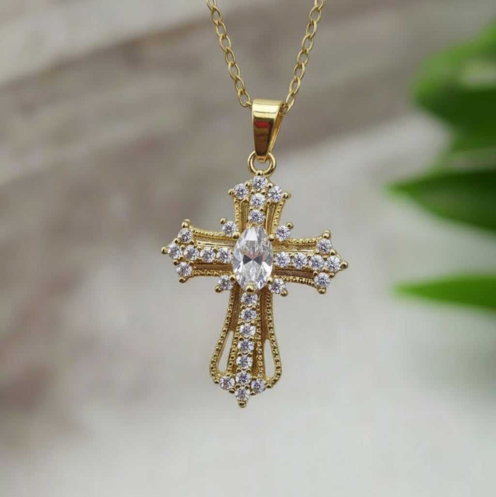 Gold cross pendant necklace on a blurred background