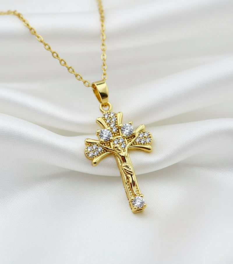 Gold cross necklace with pink stones on a white background