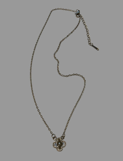 Silver necklace with a floral pendant on a light gray surface