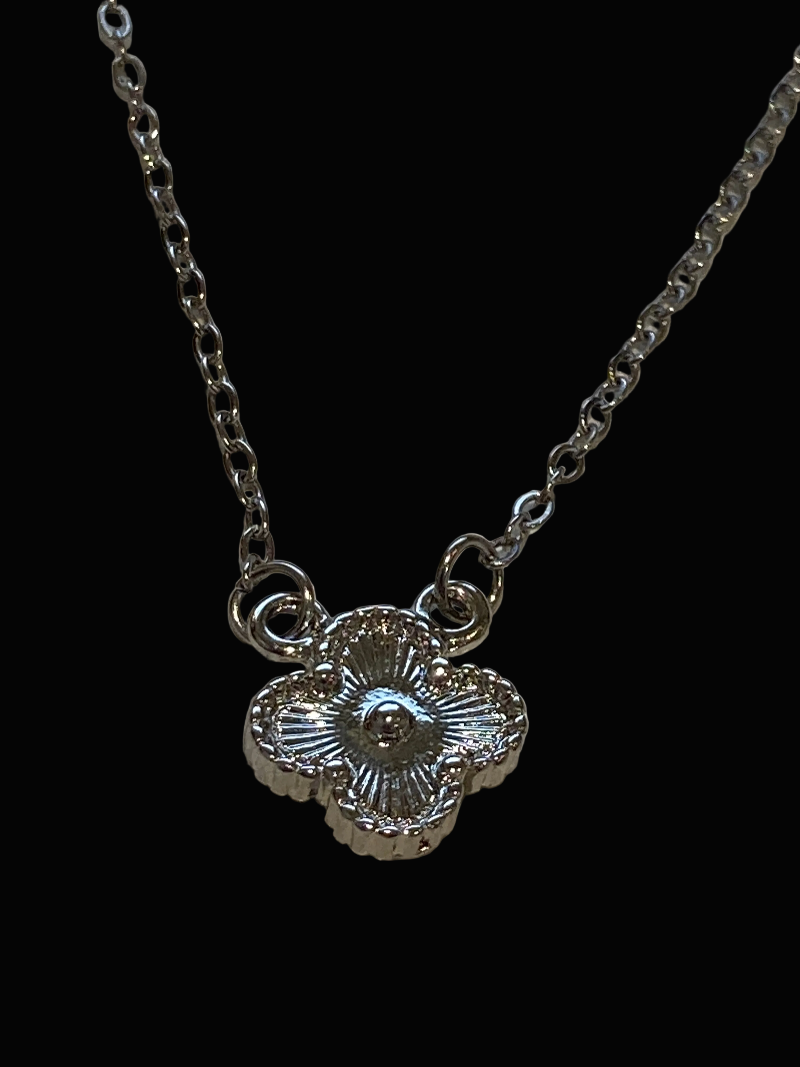 Silver necklace with a quatrefoil 
pendant on a black background