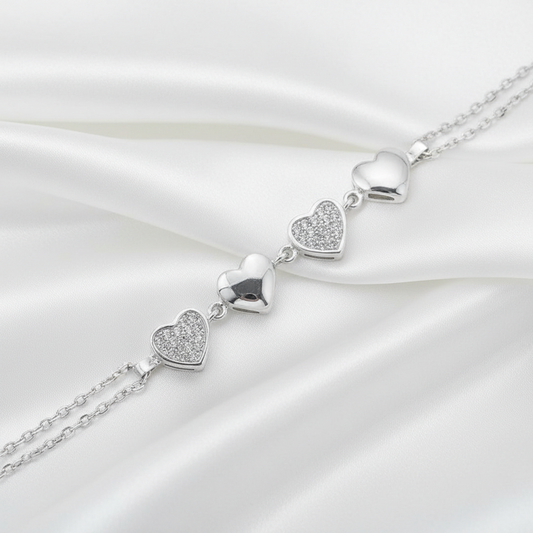 A silver heart-link chain bracelet featuring four polished and pavé-set heart charms, shown on a white background.