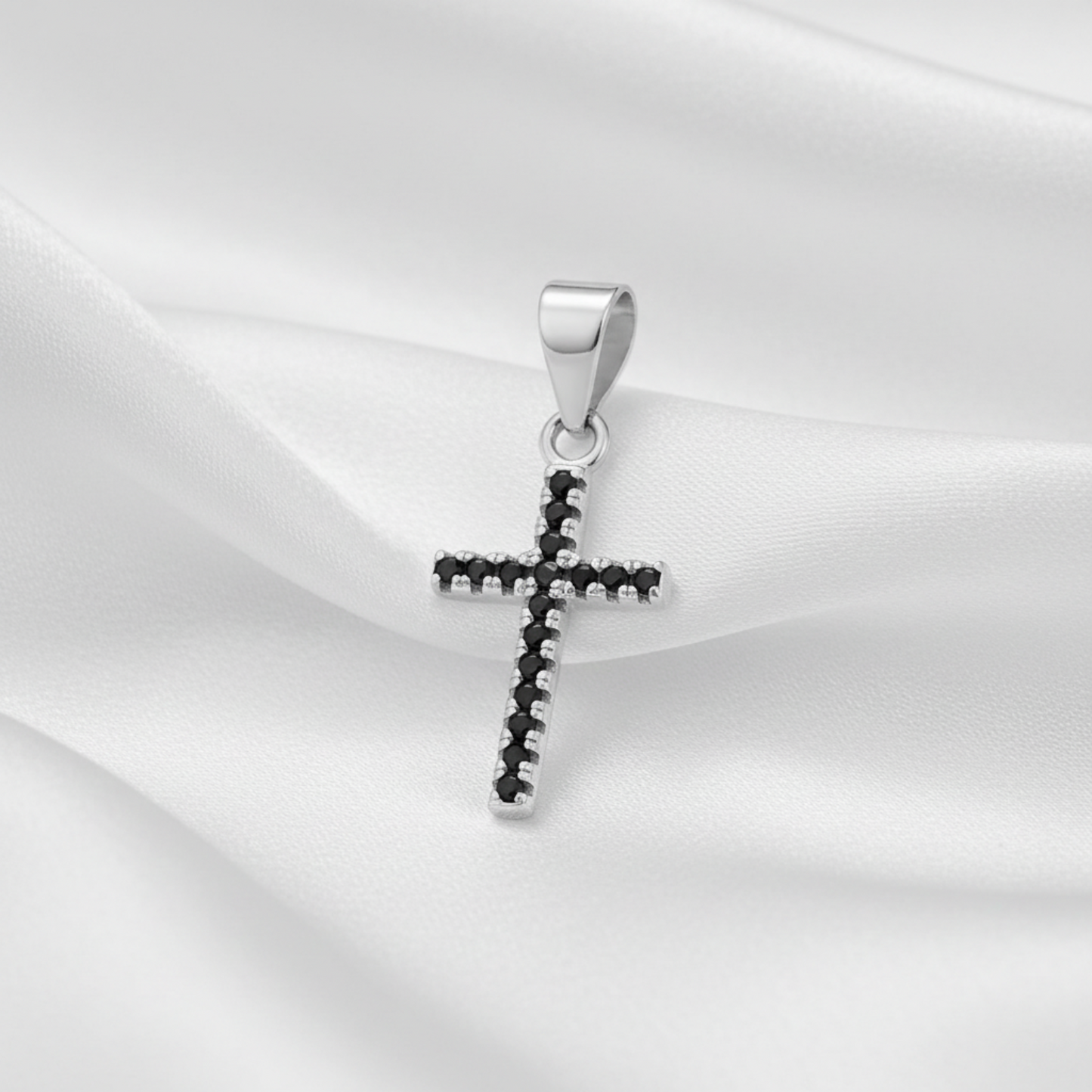 A sterling silver cross pendant featuring a row of small black gemstones along its edges, set against a plain white background.