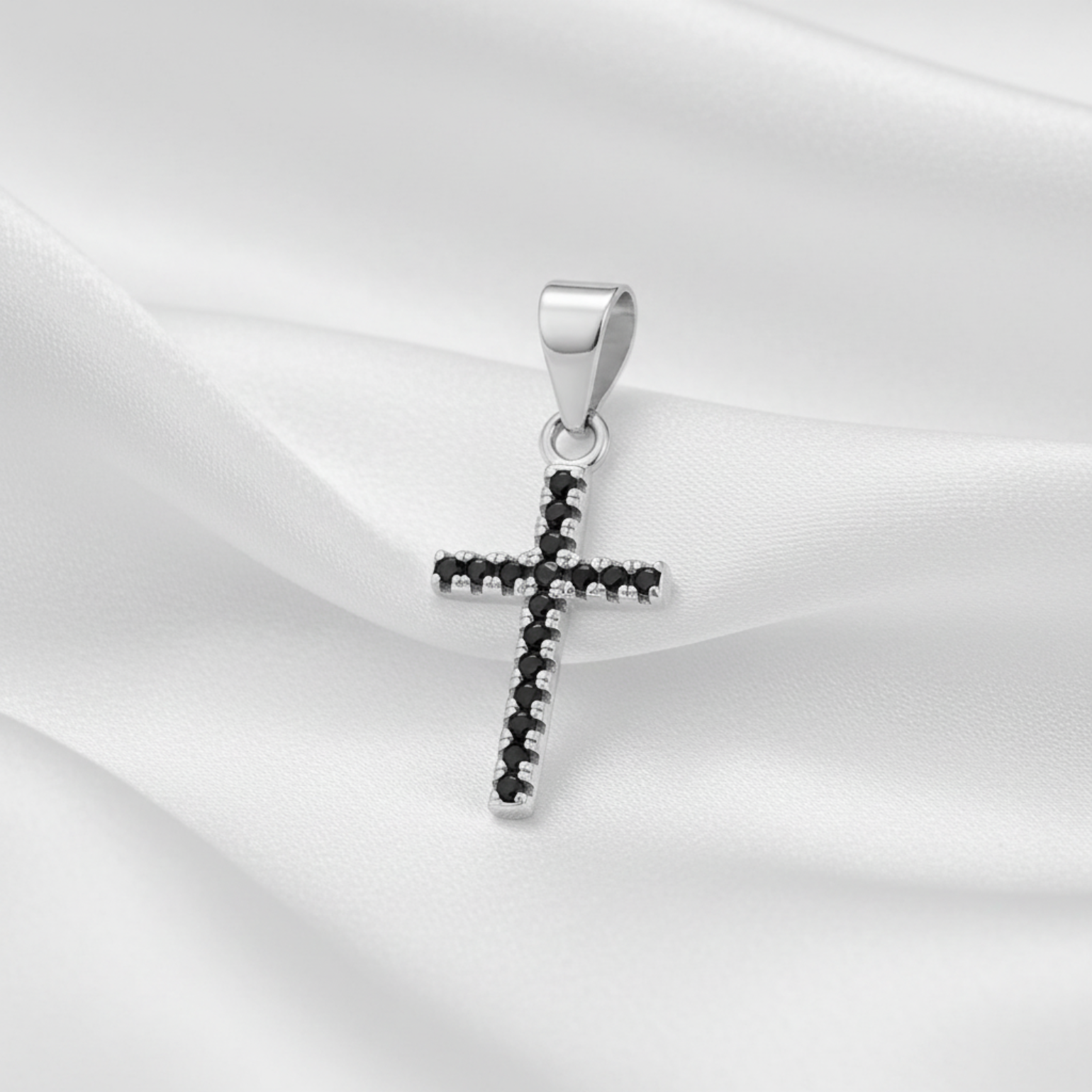 A sterling silver cross pendant featuring a row of small black gemstones along its edges, set against a plain white background.