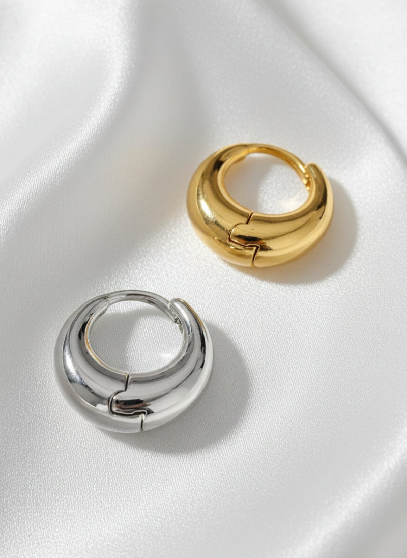 Four gold and silver hoop earrings on a white background