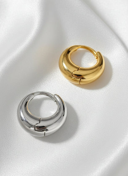 Four gold and silver hoop earrings on a white background