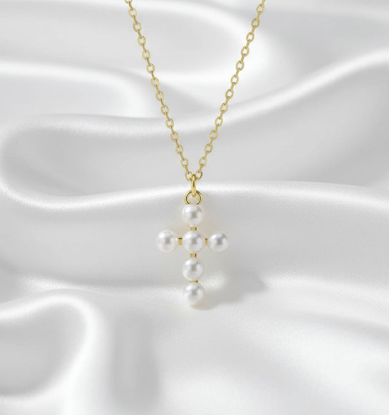 Pearl cross pendant on a gold chain against a white background