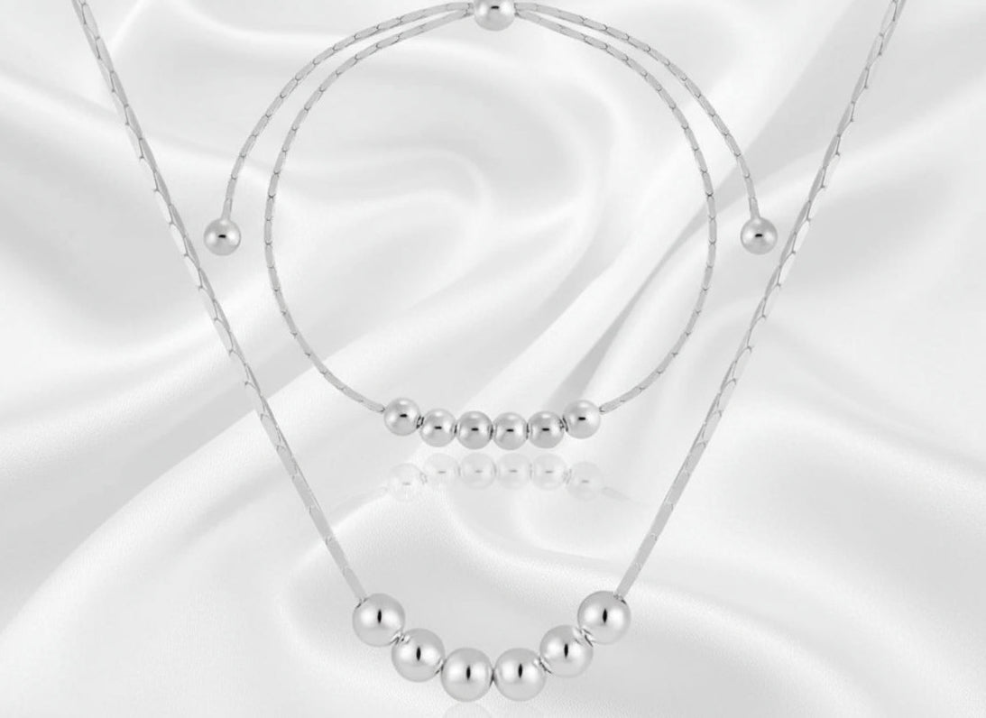 silver necklace and matching bracelet with beads on a white background