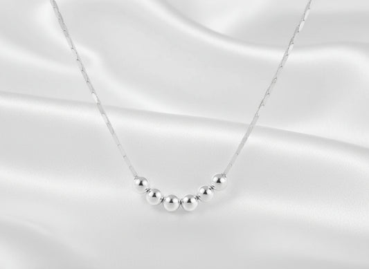 Silver necklace with five evenly spaced beads on a white background
